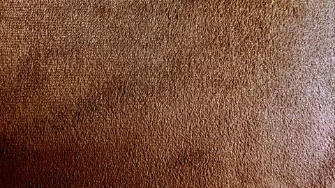 Macro brown suede fabric texture shows soft velvet grain in warm lighting for Stock Photos