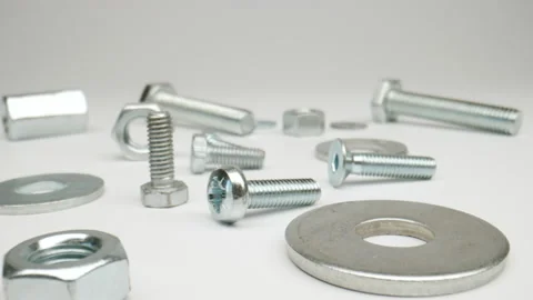 MACRO: Camera moving along lying bolts, nuts on a white background Stock Footage 174555410