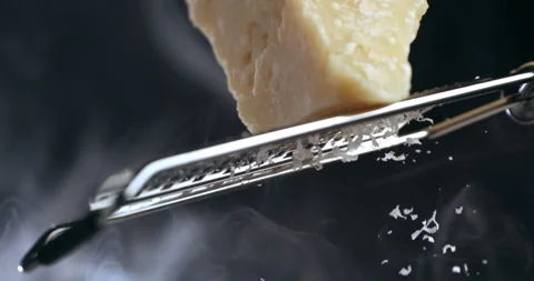 Macro of chef grates parmesan cheese with steel grater on dish for prepare pasta Video stock 269328406