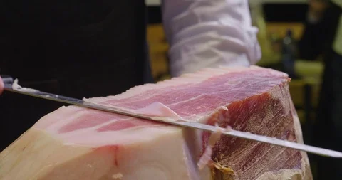 Macro of a chef who cuts a slice of ham of excellent quality with the knife. Video stock 115116488