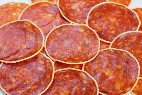 Macro circular chorizo pattern texture, repeating glossy slices with white ri Stock Photos