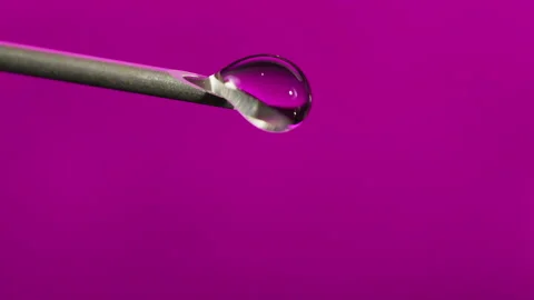 Macro Clear fluid dripping out of a Syringe needle. Biotech, Vaccine, CRISPR Stock Footage 133627632