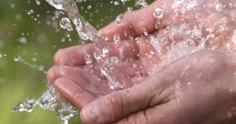Macro of clear pure water flow stream pouring to young hand with splashing drops Stock Footage 268442027