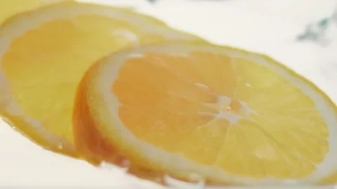 Macro close up of 3 slices of Orange  splashing in water in slow motion Stock Footage 273121823