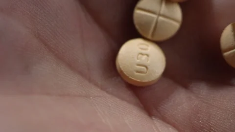 Macro close-up of amphetamine / dextroamphetamine pills dropping in a hand 스톡 동영상 106812912