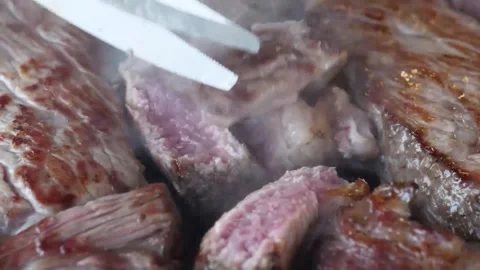 Macro Close Up of Chef Slicing Juicy Freshly Grilled Beef Steak on a Sizzling Gr Stock Footage 338210895