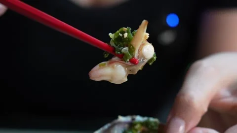 Macro Close-Up of Chopsticks Lifting Shellfish with Green Garnish Stock Footage 330061583