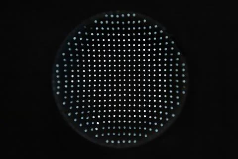 Macro close-up of a circular panel covered in uniform tiny dots over black .. Stock Photos