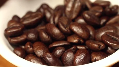 Macro close up of coffee beans falling into a white bowl Stock Footage 156460426