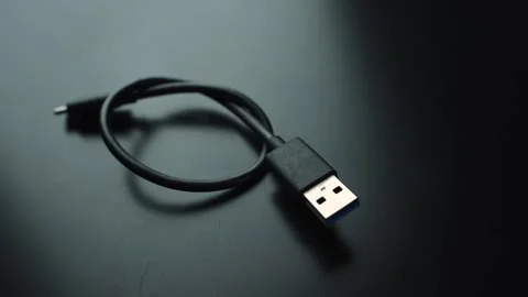 Macro close-up of a coiled black USB cable with USB-A connector on a dark desk Stock Footage 328974683