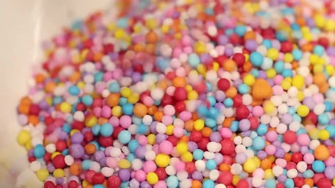 Macro close up of colored candy sprinkles falling into a white bowl Stock Footage 156455106