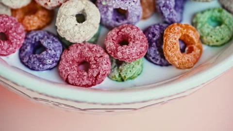 Macro close-up of colorful cereal rings with milk on a pink background Stock Footage 344687196