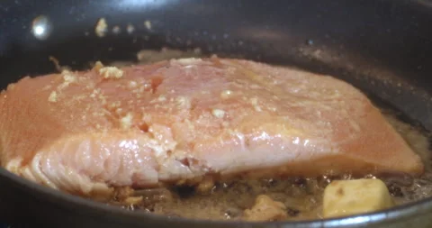 Macro Close Up of Cooking Salmon in Garlic and Butter in Cast Iron Pan Stock Footage 262100110