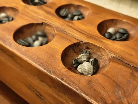 Macro close up of cowrie shells inside a carved congklak board Stock-Fotos