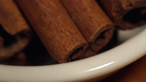 Macro close up dolly past white bowl of cinnamon sticks Stock Footage 156454916