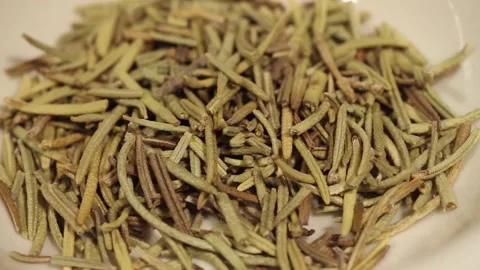 Macro close up dolly past white bowl of dried rosemary leaves Stock Footage 156456316