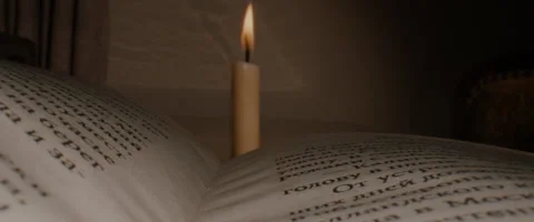 Macro close up dolly shot over opened book, candle on the background. old time.  Stock Footage 250901974