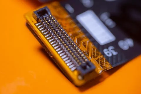 Macro close up of exposed orange printed circuit board connector with rows .. Stock-Fotos