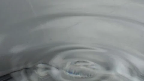 Macro Close Up of Falling Water Drop Creating Circular Ripple in Clear Liquid Stock Footage 345898268