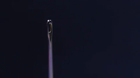 Macro close up of a female hand putting a thread through a needle Stock Footage 70244773