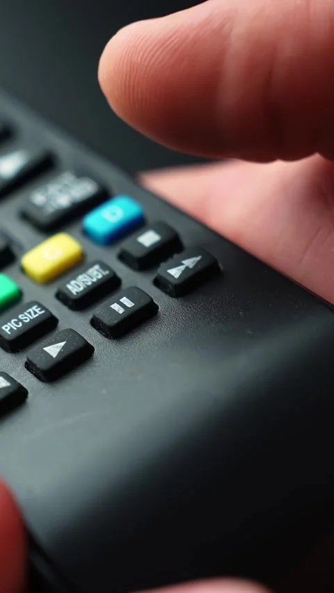 Macro close-up of a fingertip pressing the pause key on a TV remote, shallow Stock Footage 331318846