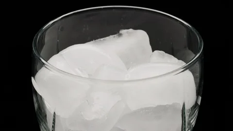 Macro close up on glass filled with ice as clear soda pours in and fizzes Stock Footage 127593109