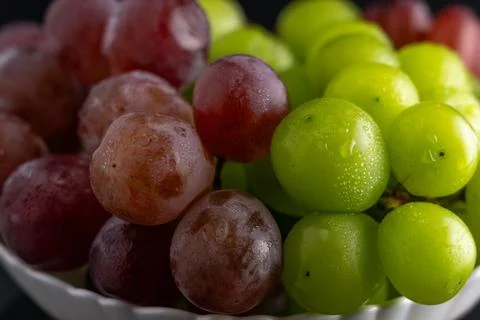 Macro Close-Up of Green and Red Grapes with Water Drops on White Plate Foto stock