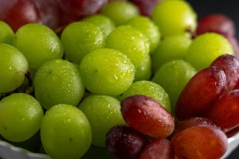 Macro Close-Up of Green and Red Grapes with Water Drops on White Plate Foto stock