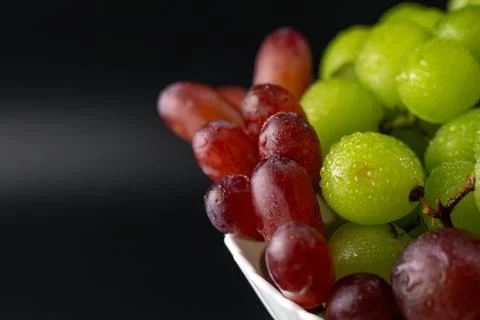 Macro Close-Up of Green and Red Grapes with Water Drops on White Plate Foto stock