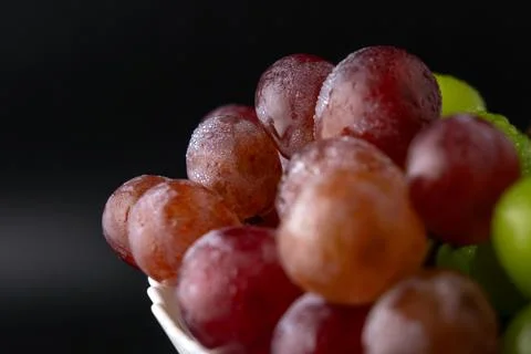 Macro Close-Up of Green and Red Grapes with Water Drops on White Plate Foto stock