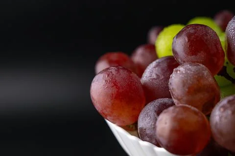 Macro Close-Up of Green and Red Grapes with Water Drops on White Plate Foto stock
