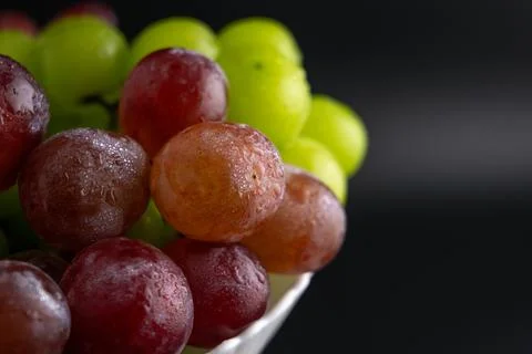 Macro Close-Up of Green and Red Grapes with Water Drops on White Plate Foto stock