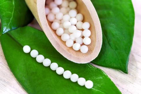 Macro close up of homeopathic pills on green leaf. Stock Photos