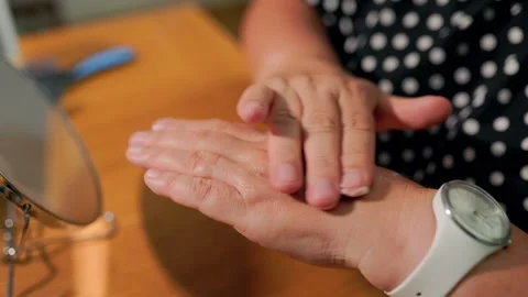 Macro close up of human hands rubbing moisturizing cosmetic cream on skin. 库存影片 339784589
