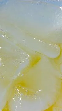 Macro Close Up of Ice Cubes in Refreshing Yellow Liquid or Cold Drink Foto stock