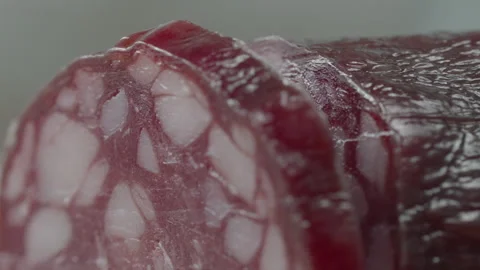 Macro close-up of a knife blade cutting a piece of smoked salami sausage Vídeo Stock 316180385