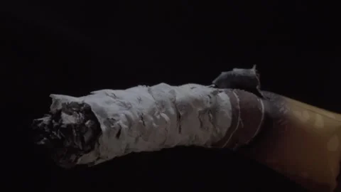 Macro Close Up of Lit Cigarette With Burning Ash Against Black Background Stock Footage 342236164