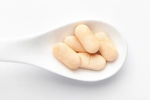 Macro Close up of medicinal or herbal light yellow tablet on a white ceramic  스톡 사진