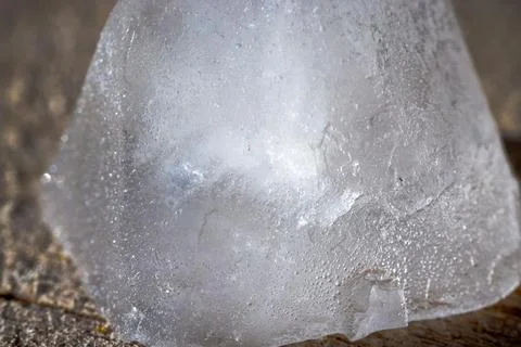 Macro close-up of a melting ice cube on a wooden surface. Foto stock
