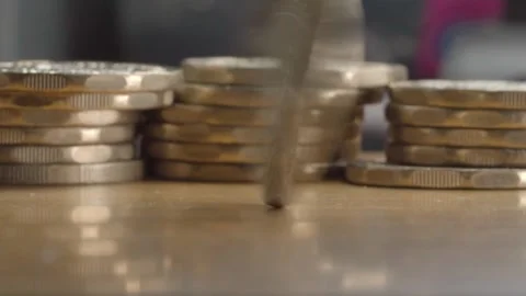 Macro Close Up of Mexican 20 Peso Coin Spinning Between Stacks of Coins on Table Stock Footage 345529882