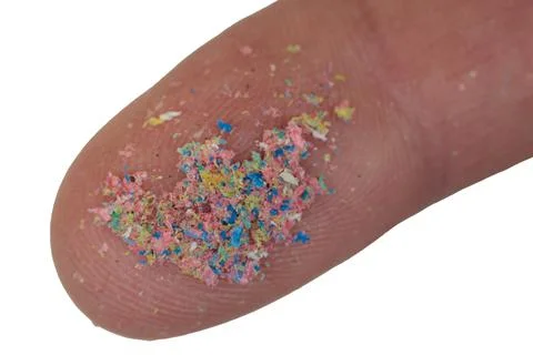 Macro close-up of a microplastic on the finger of the hand. Isolated on white Foto stock