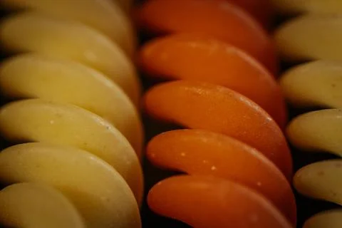 Macro close-up of multi-colored rotini pasta spirals in orange. Stock Photos