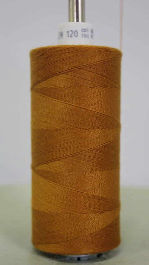 Macro close up of a mustard yellow sewing thread cone mounted on a metal spindle Stock Footage 335503856