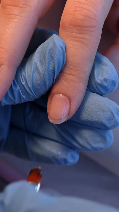 Macro close-up of a nail technician brushing product onto a client’s nude Vidéo 333653292