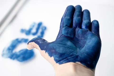 Macro close-up of an open palm covered in blue paint with. Fotos de archivo