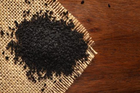 Macro close-up of Organic black cumin  (Nigella sativa) or kalonji on the woo Stock Photos