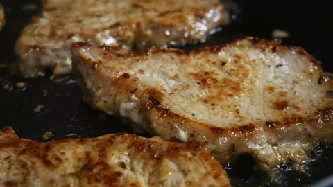 Macro close-up of pork chops in a skillet, fried in a frying pan Stock Footage 102770313
