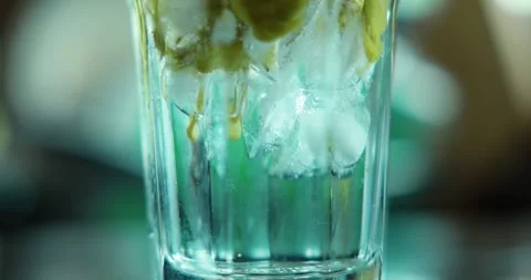 Macro close up pouring thick green matcha tea over ice cubes in a clear gla.. Stock Footage 345547610