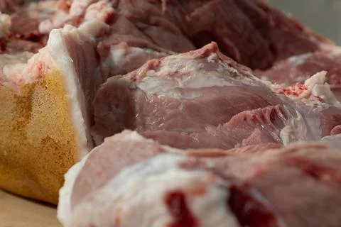 Macro close-up of raw bone-in pork leg during home butchering in a kitchen. Stock Photos