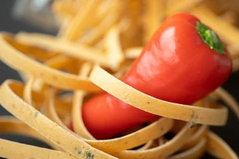 Macro close-up of a red pepper nestled in uncooked ribbon. 스톡 사진